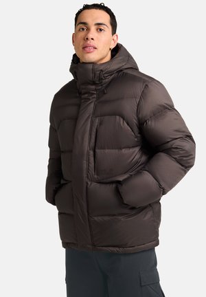 Veste matelassée rembourrée marron foncé avec un col haut, des poches avant et une fermeture éclair dissimulée. Texture lisse avec un fini mat.