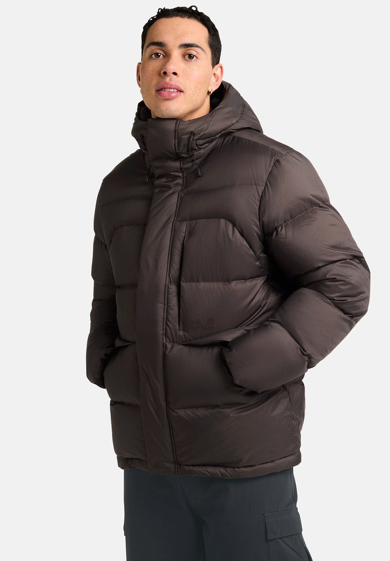 Giacca a vento imbottita di colore marrone scuro con colletto alto, tasche frontali e zip nascosta. Texture liscia con finitura opaca.