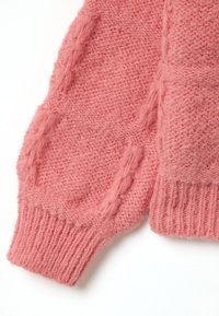 Rosa gestrickter Pullover mit einer weichen, flauschigen Textur. Verfügt über gerippte Ärmelbündchen und ein Zopfmuster entlang der Ärmel. Gemütliches und warmes Erscheinungsbild.