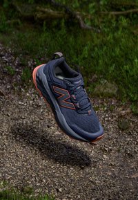 Heren hardloopschoen van ademend navy mesh materiaal met oranje accenten. Beschikt over een ronde neus, een geveerd zool en gestructureerde veters.