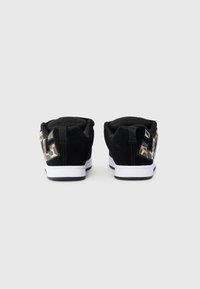 Sorte semskede joggesko med hvite såler, med en leopardmønstret detalj og logo på hælen. Minimalistisk design med en glatt tekstur.