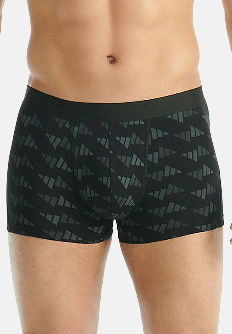 Manlig överkropp som bär svarta boxershorts med ett geometriskt triangelmönster och ett enfärgat svart midjeband.