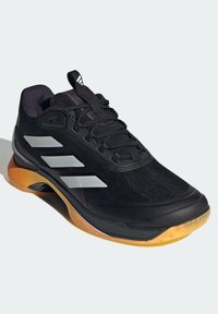 Černá atletická bota se stříbrnými akcenty, syntetický svršek, texturovaná látka, zaoblená špička a gumová podrážka s oranžovou částí.