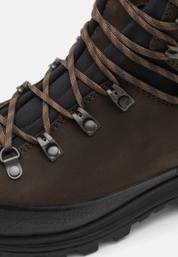 Botte de randonnée en cuir marron avec doublure en textile noir, crochets en métal et lacets marron. La semelle est noire avec un motif texturé pour une meilleure adhérence.