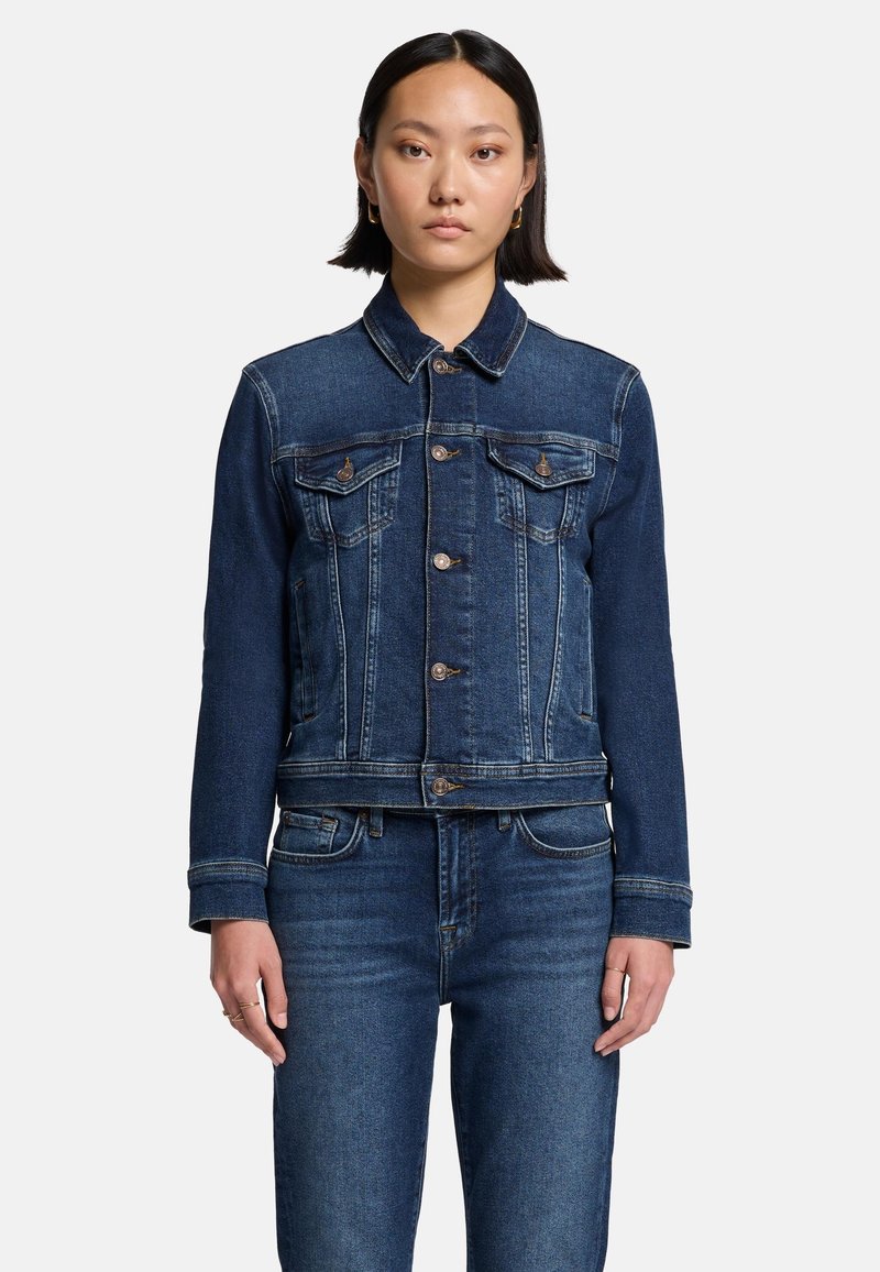 Mørkeblå denimjakke med klassisk krave, frontlukning med knapper, to brystlommer og hvide stikninger.