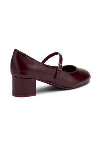 Zapatos de cuero burdeos de tacón bajo con punta redondeada y una correa diagonal, que presentan una pequeña hebilla plateada y un acabado texturizado.