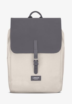 Rucsac bej cu un capac gri închis, curea din piele și cataramă metalică. Prezintă detalii cusute și un etichetă cu logo pe partea din față.