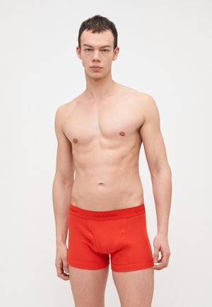 Piros pamut boxer alsónemű, szoros illeszkedéssel, fekete rugalmas derékpánttal, amelyen a "Calvin Klein" felirat szerepel. Egyszerű dizájn minta nélkül.