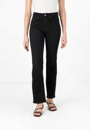 High-waisted black jeans with a flared leg, made from denim. Features classic pockets and a button closure. Paired with black strappy sandals.