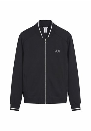 Schwarze Zip-Up-Bomberjacke mit weißem Besatz an Bündchen und Kragen, mit kleinem "AM" Logo auf der linken Brust und Fronttaschen.