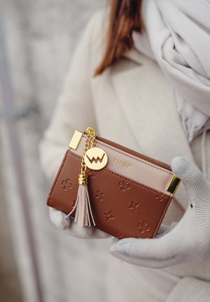 Brown faux leather wallet with gold hardware, embossed floral pattern, pink accent panel, zipper closure, and tassel detail.