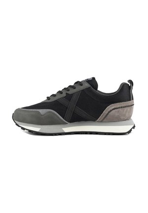 Zapatilla deportiva para hombre en negro y gris con parte superior de tela y ante, cierre de cordones, suela acolchada y lengüeta en el talón, mostrada de lado.