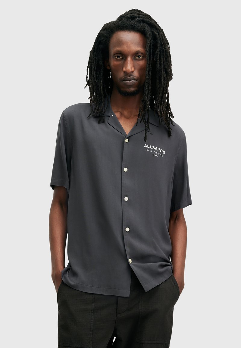 Korte mouwen, button-up shirt in donkergrijze stof, met een kraag, witte logodetail en een relaxte fit. Soepele textuur en eenvoudig ontwerp.