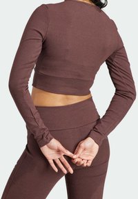 Mörkröd ribbad långärmad crop-top som matchas med högmidjade leggings, med en figurnära design och texturerad tyg.