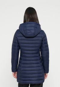 Marineblauwe pufferjack met capuchon, gekenmerkt door verticale gestikte panelen en een gladde textuur. Inclusief zijzakken en een getailleerde snit.