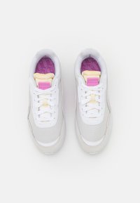 Scarpe da ginnastica bianche con una parte superiore liscia in sintetico, dettagli rosa, soletti interni a motivo viola e lacci bianchi. Punta arrotondata e suola ammortizzata.