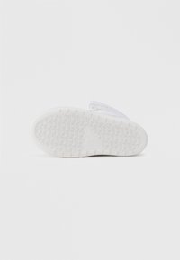Suola di sneakers bianche con motivo testurizzato, caratterizzata da un design triangolare in rilievo e bordi lisci per grip e stabilità.
