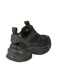 Chaussure de sport noire avec une tige en mesh texturé, une semelle épaisse en caoutchouc et un col rembourré. Dotée d'une languette arrière et d'accents de logo.