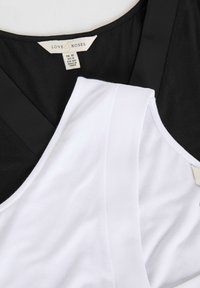 Melnbalti divslāņu topi ar V veida kaklu, ar gludu audumu un kopšanas etiķeti melnajā daļā.