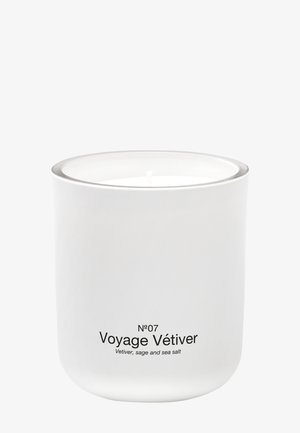 Bougie parfumée blanche dans un contenant blanc étiqueté "N°07 Voyage Vétiver" avec des notes de fragrance de vétiver, sauge et sel marin.