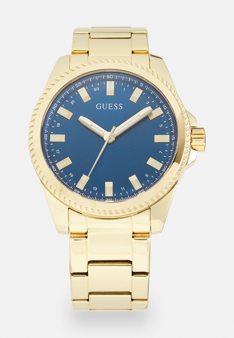 Reloj de pulsera de metal dorado con un dial azul, que cuenta con marcadores de hora blancos, agujas plateadas y un bisel texturizado, montado en una pulsera dorada.