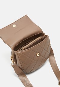 Bélelt barna bőr keresztpántos táska aranyszínű részletekkel, cipzáras zsebbel és márkázott selyemsárral. Kompakt, kerek forma, látható bélés.