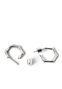 Pendientes de metal plateado con un diseño de aro angular y un brillante topito cilíndrico. Textura suave con acabado pulido y formas geométricas audaces.
