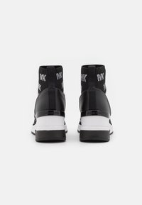 Schwarz-weiße High-Top-Sneaker mit gestricktem Knöchelkragen, der das wiederholte "MK"-Logo und Zuglaschen zeigt, von hinten betrachtet.