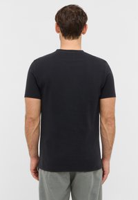 Sort T-shirt med korte ærmer og rund hals, lavet af blødt stof, med en glat tekstur og en tætsiddende design, vist fra ryggen.