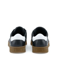Sneaker in pelle nera con dettagli bianchi, suola piatta in gomma, tacco testurizzato e logo sul retro. Design minimalista e sportivo.