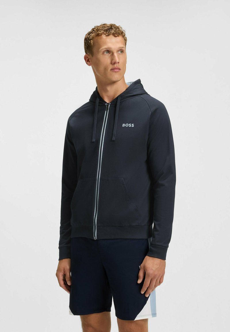 Donkerblauwe zip-up hoodie met een capuchon, lichtgrijze rits en zijzakken. Bevat het "BOSS" logo op de linker borstzone. Voorzien van een gladde textuur.