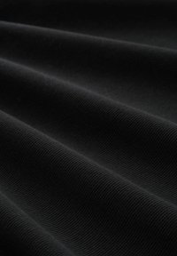 Schwarzer gerippter Stoff mit glatter Textur, der weiche Falten und ein durchgängiges Muster aufweist.