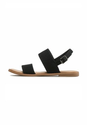 Schwarze flache Sandale mit zwei breiten Riemen und Knöchelriemen auf brauner Sohle, seitlich auf weißem Hintergrund gezeigt.