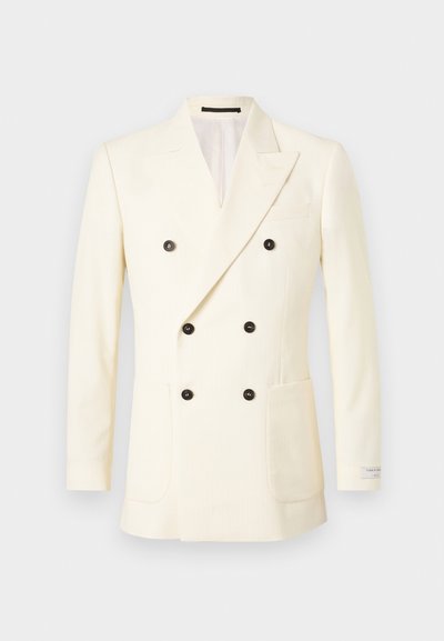 Διπλό κουμπωτό σακάκι σε κρέμε χρώμα με κάθετες ρίγες, διαθέτει μαύρα κουμπιά, κλασικές πέτες και πρακτικές πλαϊνές τσέπες.