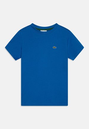 Camiseta azul de manga corta con cuello redondo y pequeño logo de cocodrilo verde bordado en el pecho izquierdo.