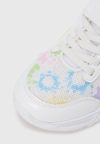 Ténis branco com parte superior em malha exibindo desenhos coloridos pintados à mão em rosa, azul e verde. Sola clara e atacadores texturizados.