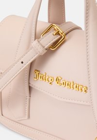 Svetloružová kožená kabelka so zlatým kovovým príslušenstvom, ktorá sa vyznačuje výrazným logom "Juicy Couture" a štruktúrovaným dizajnom.