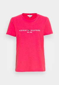 T-shirt in cotone rosa con maniche corte, scollatura tonda e logo stampato bianco "TOMMY HILFIGER EST. 1985" sul petto.