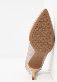 Chaussure à talon haut à bout pointu avec empeigne beige texturée et semelle à motif répétant les logos "MK".
