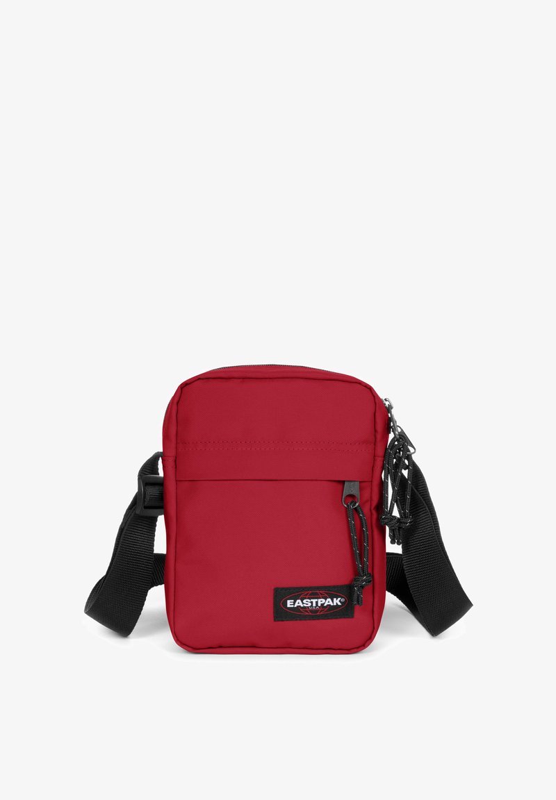Borsa a tracolla rossa in tessuto con chiusura a zip, tracolla nera regolabile, tasca frontale e patch con logo Eastpak in basso a destra.