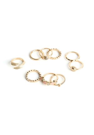 Set van negen gouden ringen met verschillende ontwerpen, waaronder eenvoudige banden, geprofileerde texturen en edelsteenaccenten op een witte achtergrond.