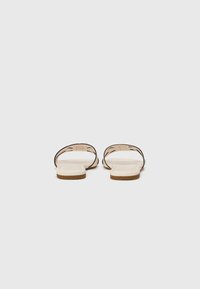 Des sandales en cuir au design minimaliste, avec deux fines sangles brunes, une semelle intérieure beige et une semelle plate brun clair.
