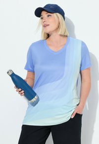 Camiseta atlética de color azul claro con cuello en V y ondas en degradé. Una gorra azul marino y una botella de agua de acero inoxidable azul con base plateada.