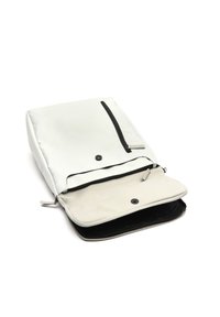 Biely syntetický batoh s čiernym zipsom, obsahujúci prednú kapsu a béžové vnútorné podšívku, s hladkou, matnou textúrou.