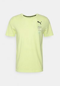 Camiseta de algodón amarilla con mangas cortas, cuello redondo y texto impreso en el lado izquierdo. Presenta un logo de Puma en negro.