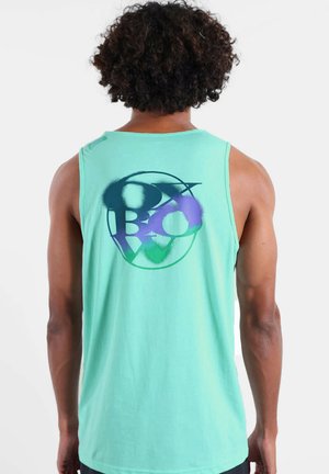 Personne aux cheveux bouclés portant un débardeur turquoise avec un motif circulaire abstrait multicolore au dos.