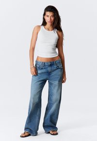 Hvit ribbet tanktop kombinert med lyseblå vide jeans. Løs passform og mid-rise design, med klassisk fem-lomme stil.