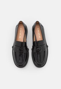 Black leather loafers with a flat sole, featuring a strap and embossed logo detail. Smooth texture with shiny finish, designed for slip-on wear.