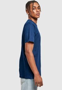 Marineblå kortærmet t-shirt, rund halsudskæring, bomuldsstof, standard pasform, ensfarvet design, båret med lyse denim jeans.