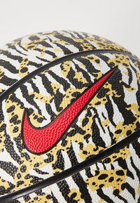 Nike basketball featuring a textured design with black, yellow, and white tiger stripes, accented by a prominent red logo and black panels.